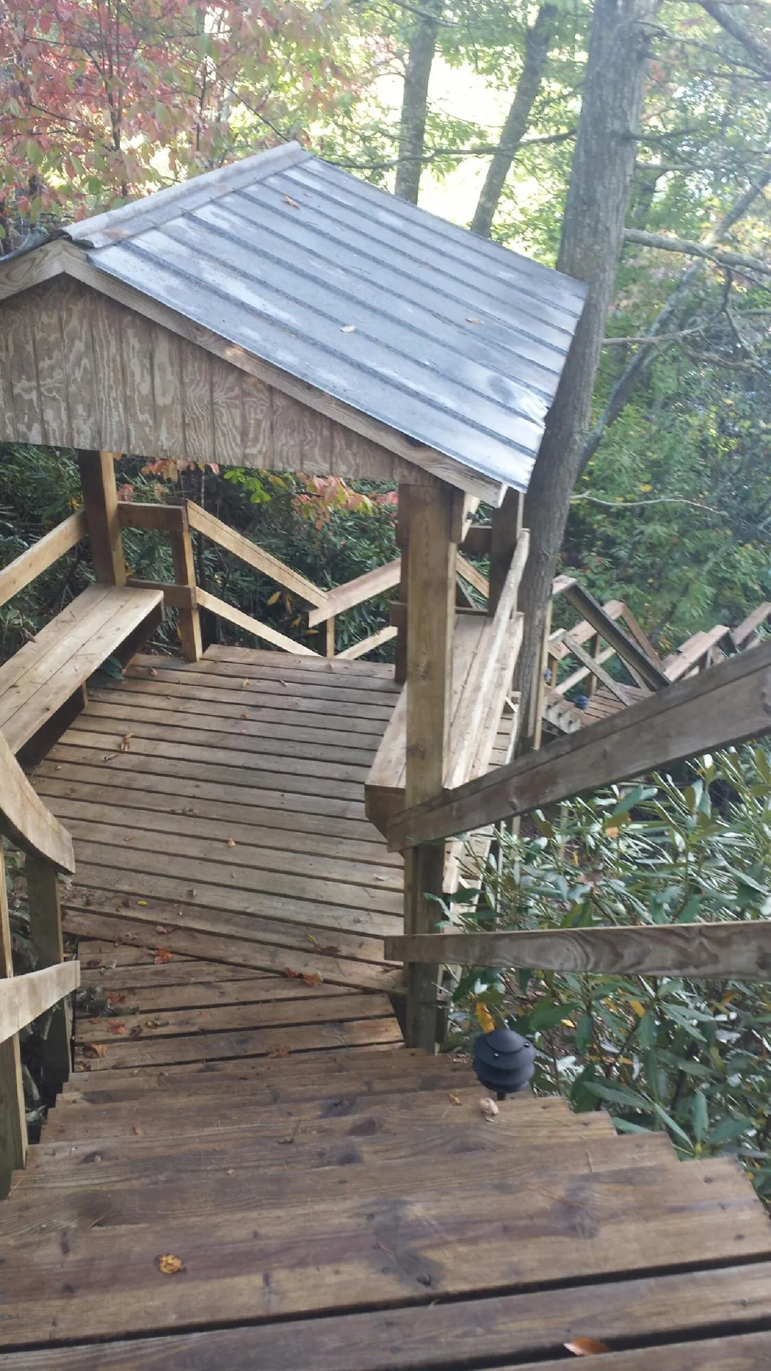Metal roofed shelter over wooden steps on a wooded walkway — Skylight Repair & Installation work by our crew in Montpelier